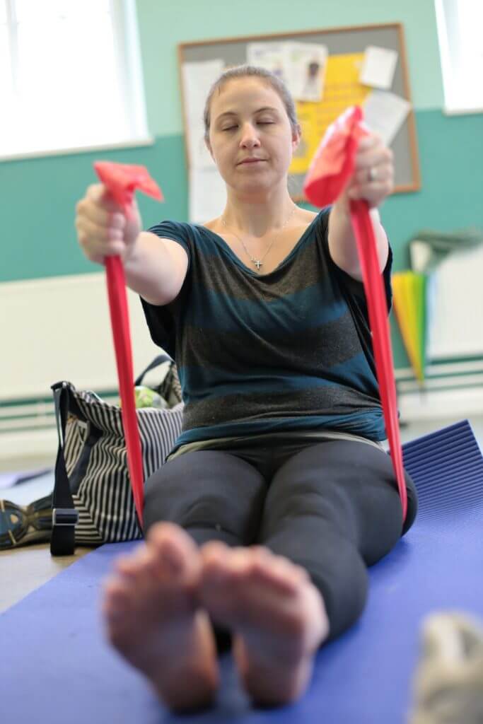 Woman working in a pilates class with a band.