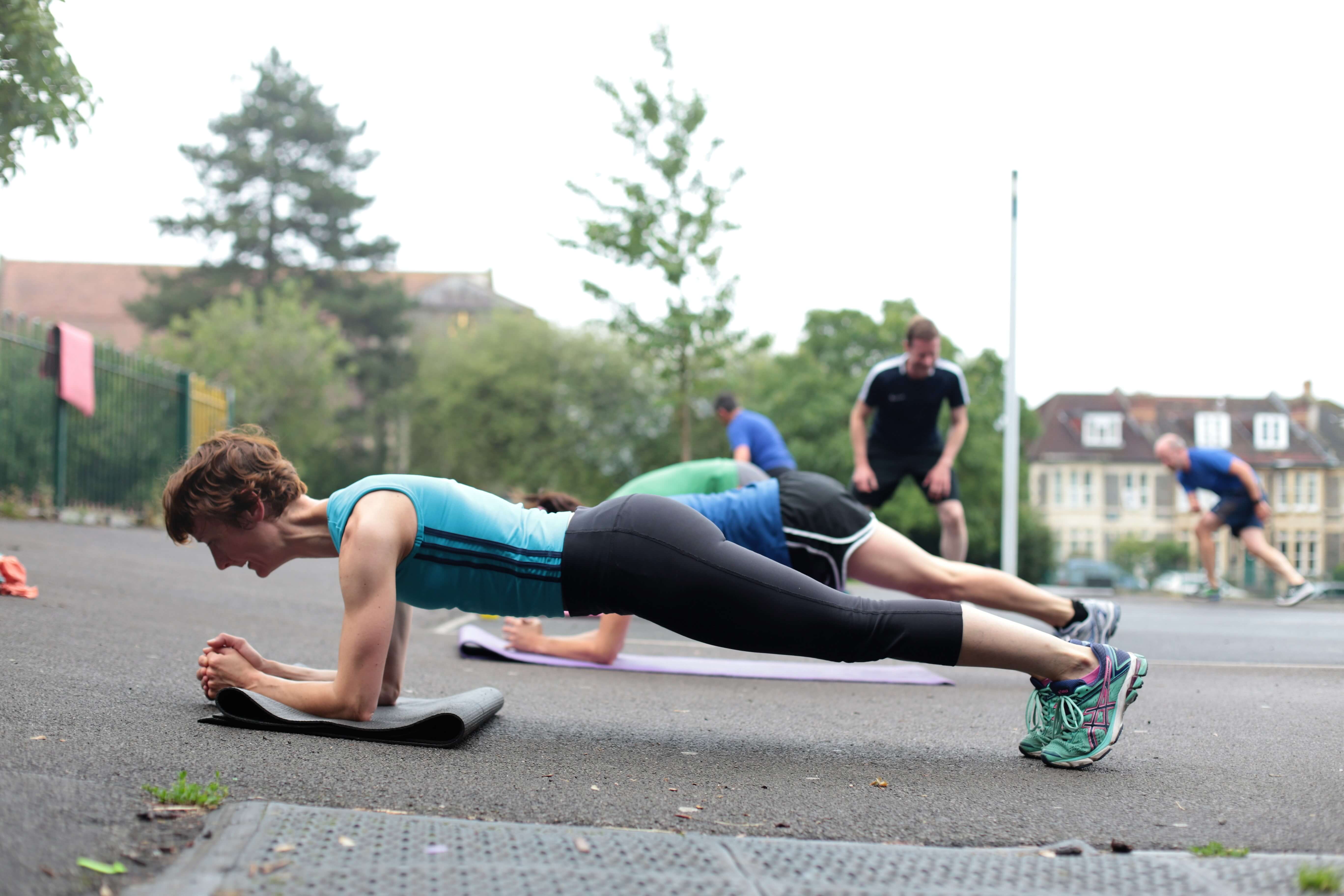 Lady doing a plank exercise at an outside exercise class outdoors bootcamp..