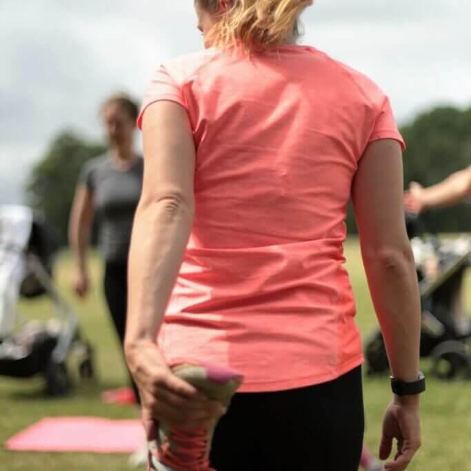 back of a lady doing a hamstring stretch.